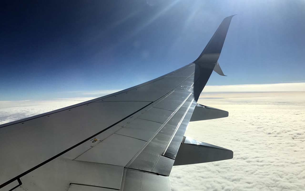 2017 Travel Year. Airplane wing in flight over clouds.
