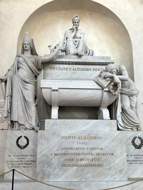 3 statues sitting on tomb.