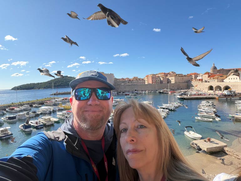 Photo of Anna and Gordon with the Harbour in the background and doves in flight.