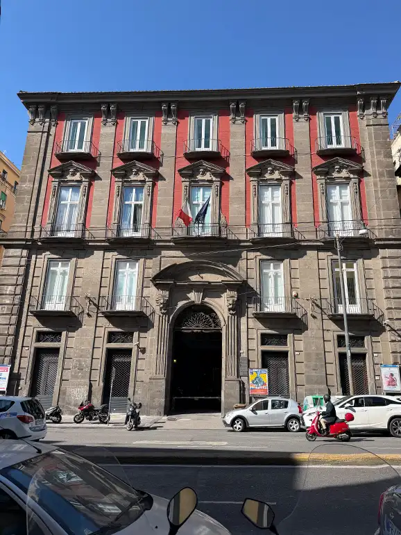 Palazzo Giordano four story building with top two floors painted red and bottom is brown.
