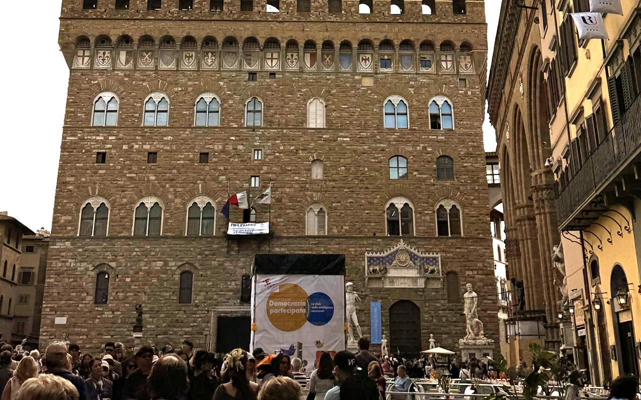Palazzo Vecchio. Brown building with people and statues in front of it.