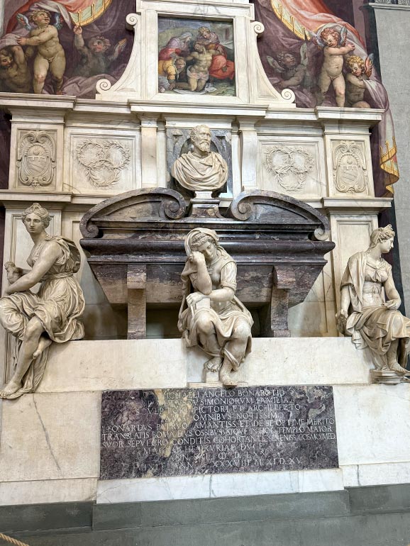 4 statues sitting on tomb with baby cherubs in the background.