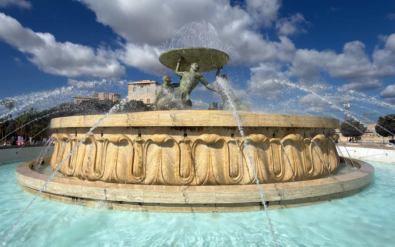 Tritons Fountain Tritons Fountain with water coming out of statues. Cloudy sky in the background.