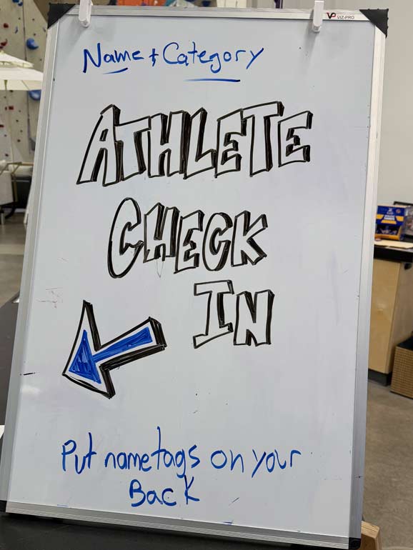 Athlete Check In A close-up shot of the athlete check-in and registration sign at the entrance of the Movement Centennial climbing gym for the Mile High Melee bouldering competition.